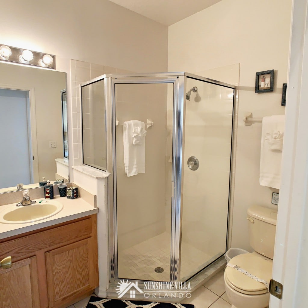 Bathroom near the two twin bedrooms at Sunshine Villa at Glenbrook Resort, a short-term vacation rental home in Orlando near Walt Disney World. A shower stall, vanity and a toilet.